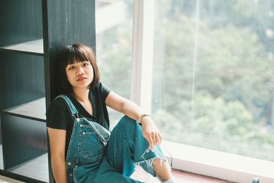 Portrait of young woman sitting by window