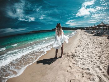 Woman standing on beach by sea against sky