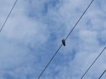 Low angle view of power lines against cloudy sky