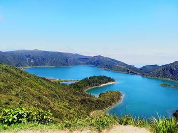 Scenic view of lake and mountains against clear blue sky