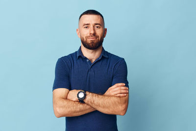 Portrait of young man standing against blue background