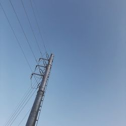 Low angle view of electricity pylon against clear sky