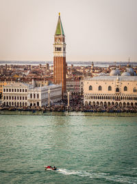 Buildings by sea against clear sky