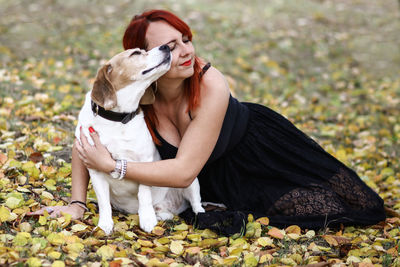 Woman embracing dog while sitting on field