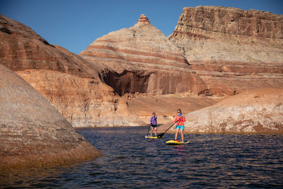 People walking on rock formation in water