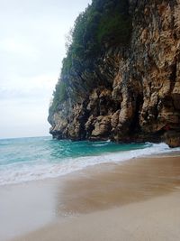 Rock formation on beach against sky