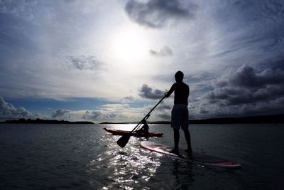 Silhouette man standing by sea against sky