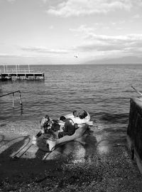 People sitting by sea against sky