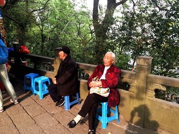 Full length of man sitting on bench in park
