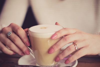 Midsection of woman holding coffee cup on table