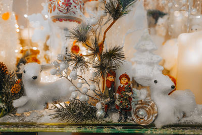 White toy fawns and christmas tree branch with silver glitter on a festive storefront. new year 2022