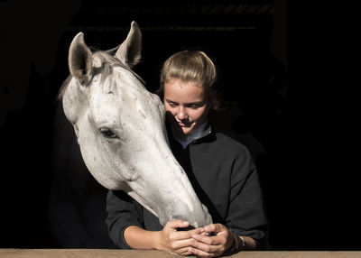 Young woman by horse against black background