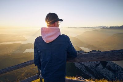 Rear view of man looking at mountains against sky