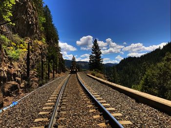 Train on railroad track amidst trees against blue sky