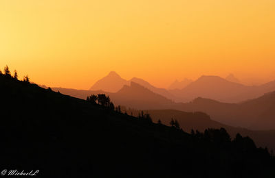 Scenic view of silhouette mountains against orange sky