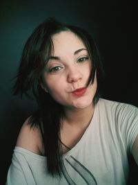 Close-up portrait of young woman against black background