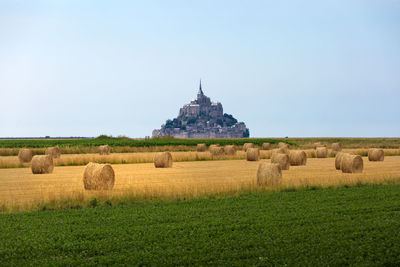 Hay bales on field against clear sky