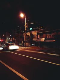 Road passing through illuminated city at night