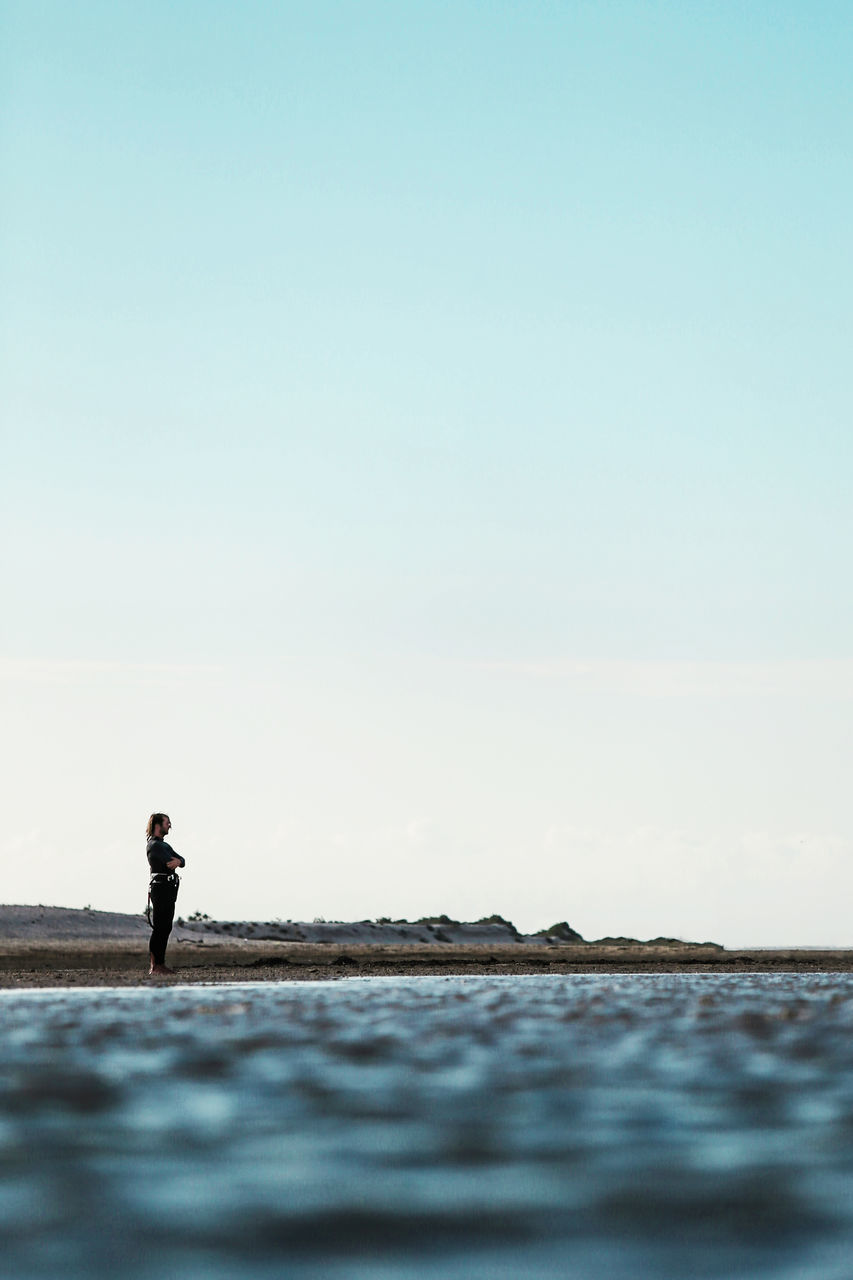 sky, one person, copy space, standing, sea, real people, beauty in nature, clear sky, scenics - nature, water, lifestyles, land, nature, leisure activity, tranquil scene, tranquility, men, day, outdoors, horizon over water