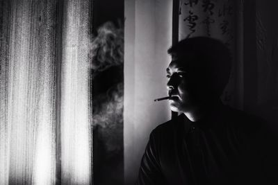 Man smoking cigarette against window