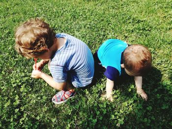 High angle view of boy with brother on grassy field