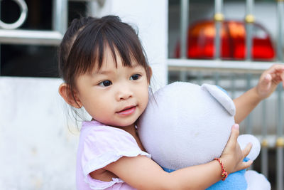 Cute girl looking away while holding toy sitting at home