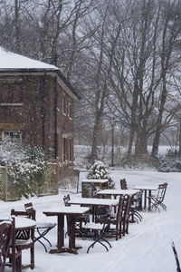 Empty chairs and tables on snow covered landscape