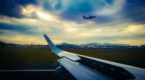 Airplane flying over airport runway against sky