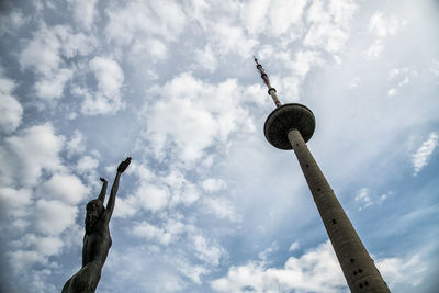 Low angle view of communications tower against cloudy sky