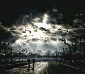 Silhouette man on river by city against sky