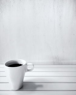 Close-up of coffee cup on table against wall