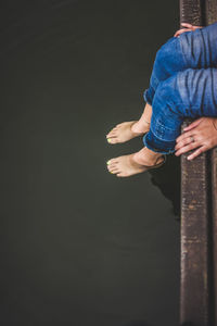 Low section of woman sitting on pier 