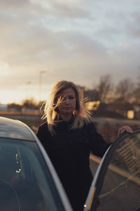 Portrait of young woman sitting on car