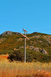 Low angle view of wind turbines on field against clear blue sky