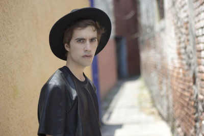 Portrait of young man standing against wall