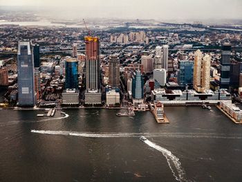 Aerial view of river and buildings against sky in city