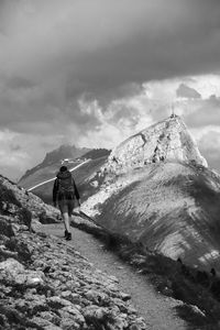 Rear view of man walking on snow covered mountain against sky