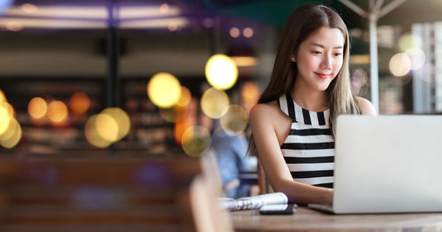 Young woman using phone on table