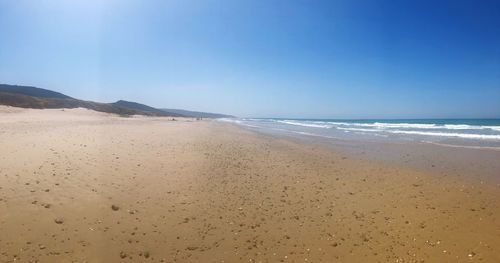 Scenic view of beach against clear blue sky