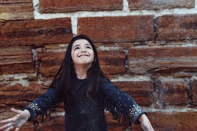 Playful girl playing with glitter against brick wall