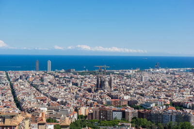 Aerial view of townscape by sea against sky