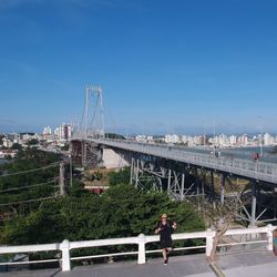 Bridge over river by city against blue sky