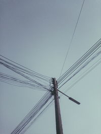 Low angle view of electricity pylon against clear sky