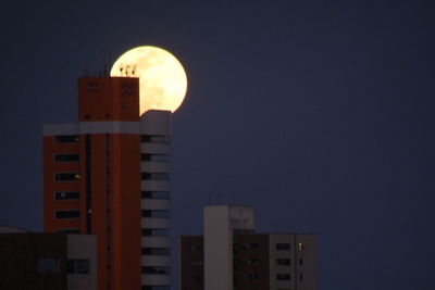 Low angle view of illuminated buildings against blue sky