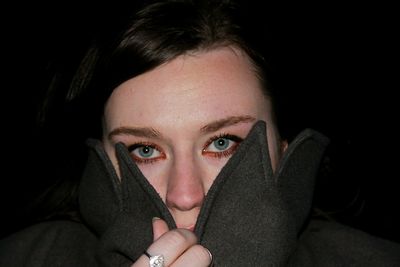 Close-up portrait of beautiful young woman against black background