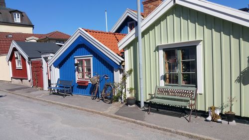 Houses on road amidst buildings against blue sky