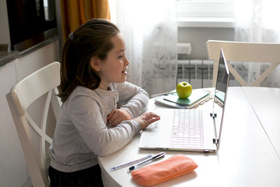 Side view of girl studying over laptop at home