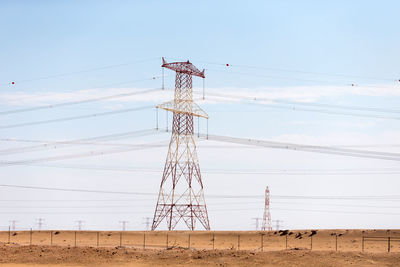 Low angle view of electricity pylon on field against sky