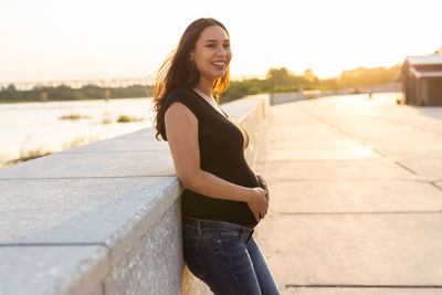 Portrait of smiling young woman standing against sky