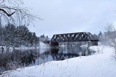 Built structure by trees against sky during winter